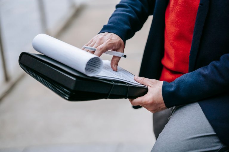 Close-up of a professional person reviewing documents outdoors. Engaged in work with focus on writing materials. — A Brief Gu