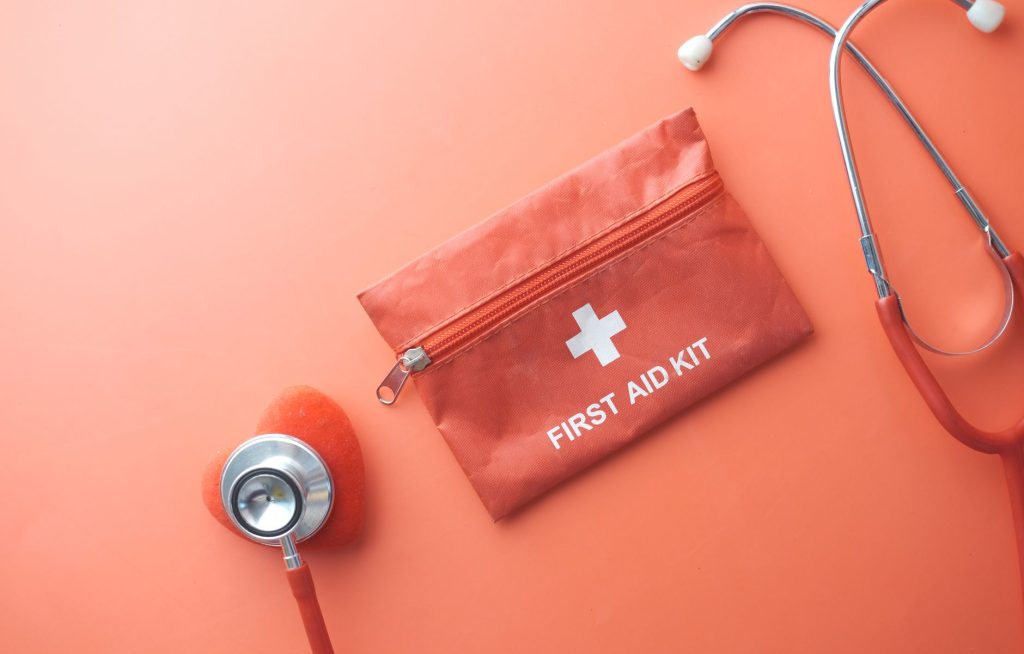 Medical tools including a stethoscope and first aid kit on a pink surface, perfect for healthcare themes. — Experience the Be