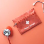 Medical tools including a stethoscope and first aid kit on a pink surface, perfect for healthcare themes. — Experience the Be