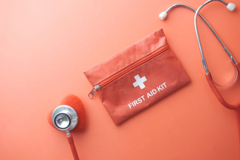 Medical tools including a stethoscope and first aid kit on a pink surface, perfect for healthcare themes. — Experience the Be