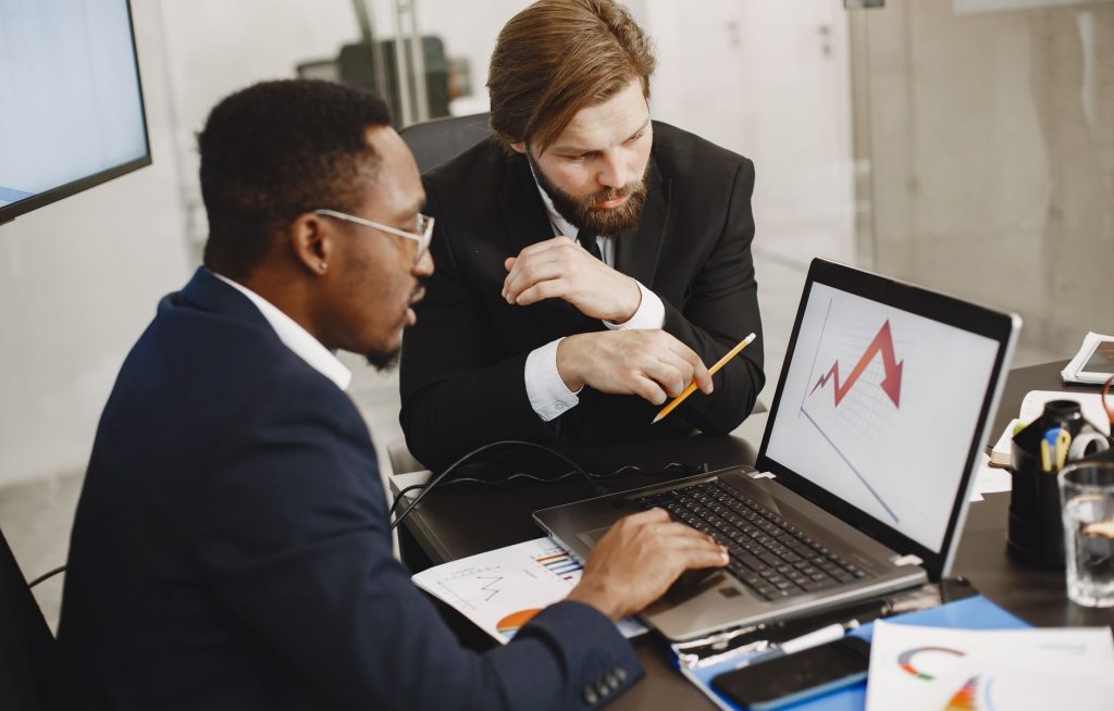 Two business professionals discuss marketing data on a laptop in a modern office. — From Click to Cannabis: A Beginner's Guid