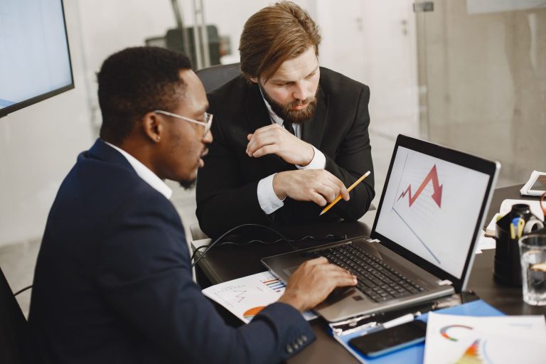 Two business professionals discuss marketing data on a laptop in a modern office. — From Click to Cannabis: A Beginner's Guid