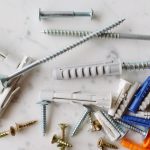 Set of various multicolored plastic dowels with metal screws of different sizes placed on white marble table in modern worksh